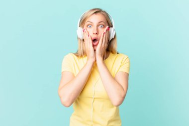 young blonde woman feeling shocked and scared and listening music.