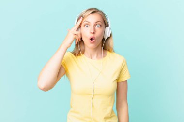 young blonde woman looking surprised, realizing a new thought, idea or concept and listening music.