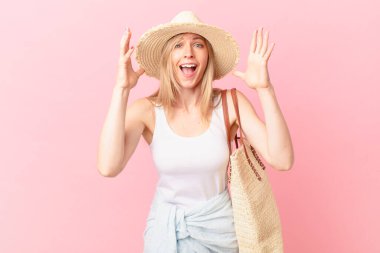 Genç sarışın kadın ellerini havaya kaldırarak çığlık atıyor. yaz konsepti