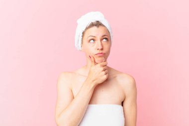 Genç sarışın kadın düşünüyor, kuşkulu ve şaşkın hissediyor ve duştan sonra