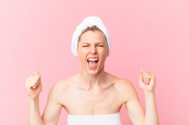 Genç sarışın kadın kızgın bir ifadeyle ve duştan sonra agresif bir şekilde bağırıyor.