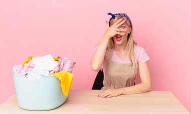 Genç sarışın kadın şok olmuş, korkmuş ya da dehşete düşmüş gibi görünüyor, yüzünü eliyle kapatıyor. çamaşır konsepti