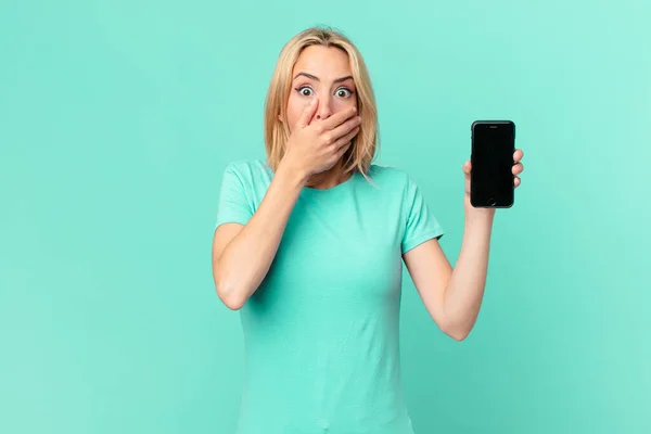Młoda Blondynka Zakrywa Usta Dłońmi Szoku Trzyma Smartfon — Zdjęcie stockowe