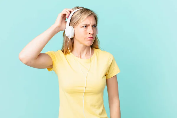 Young Blonde Woman Feeling Puzzled Confused Scratching Head Listening Music — Foto Stock