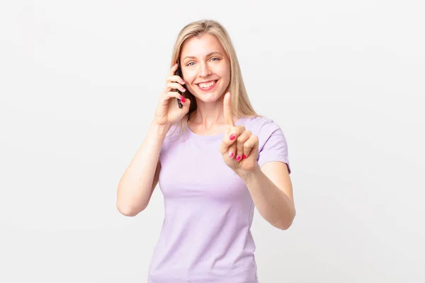 Jovem Loira Sorrindo Olhando Amigável Mostrando Número Chamando Com Telefone — Fotografia de Stock