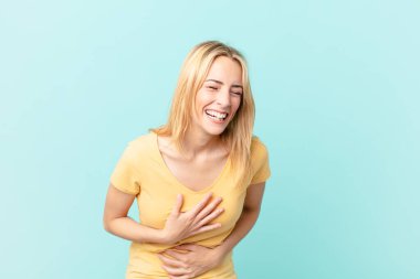 Genç sarışın bir kadın komik bir şakaya yüksek sesle gülüyor.