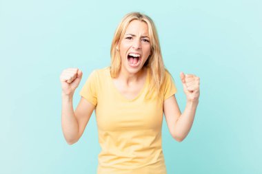 Genç sarışın kadın sinirli bir ifadeyle agresif bir şekilde bağırıyor.