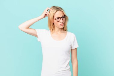 Kafası karışmış, kafası karışmış, kaşınan genç sarışın kadın.