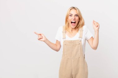 Genç sarışın kadın sinirli bir ifadeyle agresif bir şekilde bağırıyor.