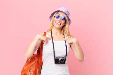 Genç sarışın kadın kendini mutlu hissediyor ve heyecanlı bir şekilde kendini işaret ediyor. yaz konsepti