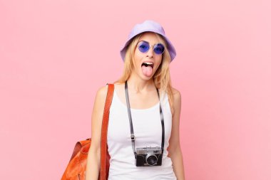 Genç, sarışın, neşeli ve asi tavırlı, şaka yapan ve dilini dışarı çıkaran bir kadın. yaz konsepti