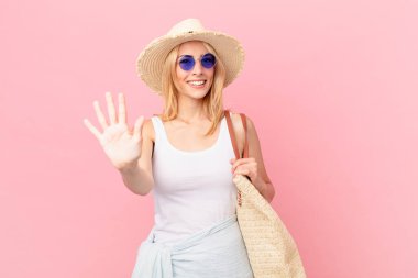 Genç sarışın kadın gülümsüyor ve arkadaş canlısı görünüyor, beş numarayı gösteriyor. yaz konsepti