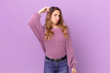 Güzel kadın şaşkın ve kafası karışmış hissediyor, başını kaşıyor.