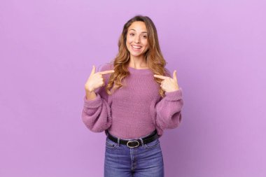 Güzel bir kadın mutlu hissediyor ve heyecanla kendini işaret ediyor.