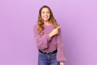 Güzel bir kadın neşeyle gülümsüyor, mutlu hissediyor ve bir tarafı işaret ediyor.