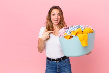 Güzel bir kadın heyecanlı ve şaşırmış görünüyor. Yan tarafı gösteriyor ve çamaşırları yıkıyor..