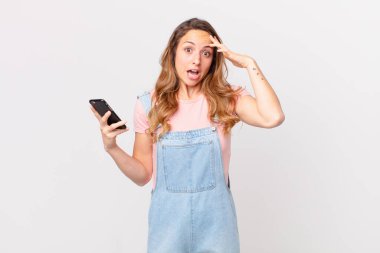 Güzel kadın şaşırmış görünüyor, yeni bir düşünce, fikir ya da konsept fark ediyor ve elinde bir akıllı telefon tutuyor.