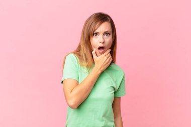 Ağzı ve gözleri açık, elleri çenesinde güzel, yetişkin bir kadın.