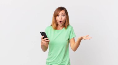 Güzel bir kadın şok geçirir, şaşırır ve akıllı telefon kullanır.