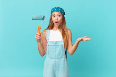 Güzel bir kadın son derece şaşırmış ve şok olmuş hissediyor. Yeni bir ev duvarı boyuyor.