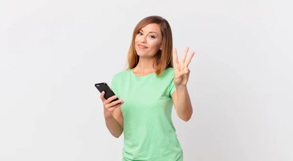 Pretty Woman Smiling Looking Friendly Showing Number Three Using Smartphone — Stock Photo, Image