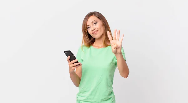 Pretty Woman Smiling Looking Friendly Showing Number Four Using Smartphone — Stock Photo, Image