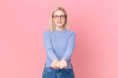 Sarışın, güzel bir kadın. Mutlu bir şekilde gülümsüyor.