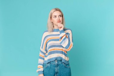 Sarışın, güzel bir kadın. Düşünüyor, kuşkulu ve kafası karışık.