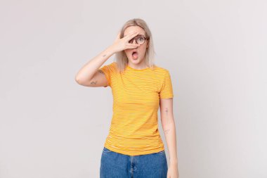 Sarışın, güzel bir kadın. Şok olmuş, korkmuş ya da korkmuş görünüyor.