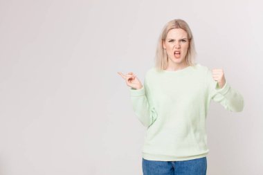 Sarışın, güzel bir kadın kızgın bir ifadeyle agresif bir şekilde bağırıyor.