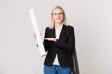 Sarışın, güzel bir kadın, neşeli bir şekilde gülümsüyor, mutlu hissediyor ve bir konsept gösteriyor. mimar konsepti