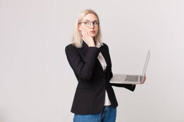 Sarışın, güzel bir kadın. Sıkılmış, hayal kırıklığına uğramış ve uykulu. Yorgun ve dizüstü bilgisayar tutuyor.