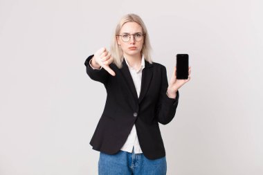 Sarışın, güzel bir kadın kendini kötü hissediyor, baş parmağını kaldırıyor ve elinde bir cep telefonu tutuyor.