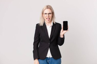 Sarışın, güzel bir kadın. İğrenmiş ve rahatsız olmuş hissediyor. Dili dışarıda ve elinde bir cep telefonu tutuyor.