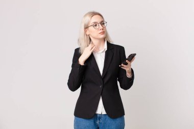 Sarışın, güzel bir kadın kibirli, başarılı, pozitif ve gururlu görünüyor ve elinde cep telefonu var.