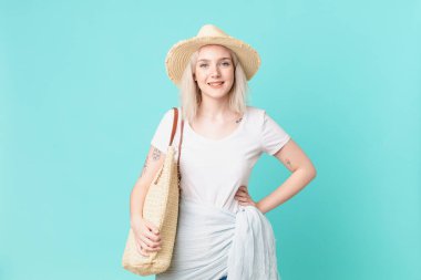 Sarışın, güzel bir kadın mutlu bir şekilde gülümsüyor, eli kalçasında ve kendinden emin. yaz konsepti