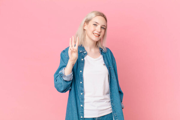 Красивая женщина улыбается и выглядит дружелюбно, показывая номер три