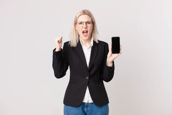 Blondynka Ładna Kobieta Krzyczy Agresywnie Wściekłym Wyrazem Twarzy Trzyma Telefon — Zdjęcie stockowe