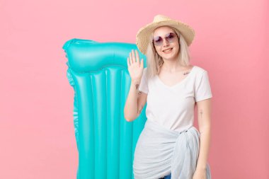 Sarışın, güzel, mutlu bir şekilde gülümseyen, el sallayan, seni selamlayan bir kadın. yaz konsepti