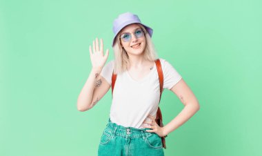 Sarışın, güzel, mutlu bir şekilde gülümseyen, el sallayan, seni selamlayan bir kadın. yaz konsepti