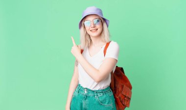 Sarışın, güzel bir kadın, neşeli bir şekilde gülümsüyor, mutlu hissediyor ve bir tarafı işaret ediyor. yaz konsepti