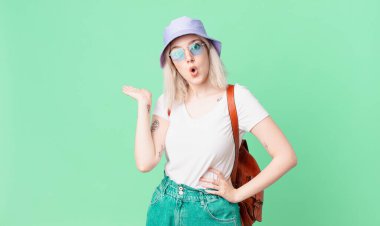 Sarışın, güzel bir kadın şaşırmış ve şok olmuş görünüyor. Çenesi düşmüş, elinde bir nesne var. yaz konsepti