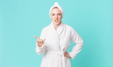 Sarışın, güzel bir kadın kızgın, sinirli, sinirli ve bornoz giyiyor.