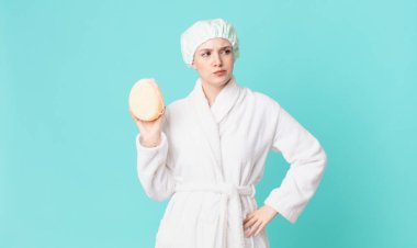 Sarışın, güzel bir kadın üzgün, üzgün ya da kızgın ve yan tarafa bakıyor ve bornoz giyiyor.