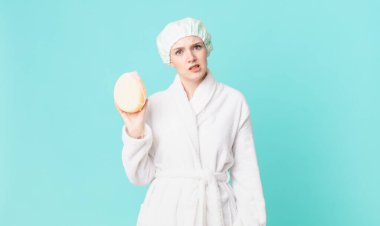 Şaşkın, kafası karışmış ve bornoz giymiş sarışın güzel bir kadın.