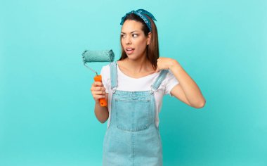 young hispanic woman feeling stressed, anxious, tired and frustrated and painting a wall