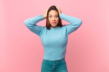 Genç İspanyol kadın stresli, endişeli ya da korkmuş hissediyor, elleri başının üstünde.