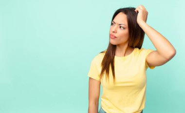 Genç İspanyol kadın şaşkın ve kafası karışık, kaşınıyor.