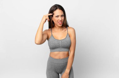 Genç İspanyol kadın şaşkın ve şaşkın hissediyor, senin deli olduğunu gösteriyor. fitness konsepti