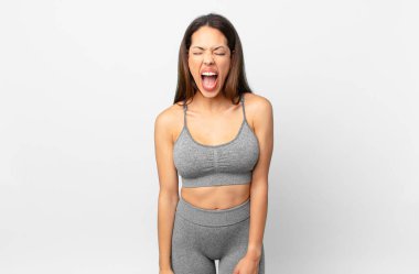 Genç İspanyol kadın agresif bir şekilde bağırıyor, çok kızgın görünüyor. fitness konsepti